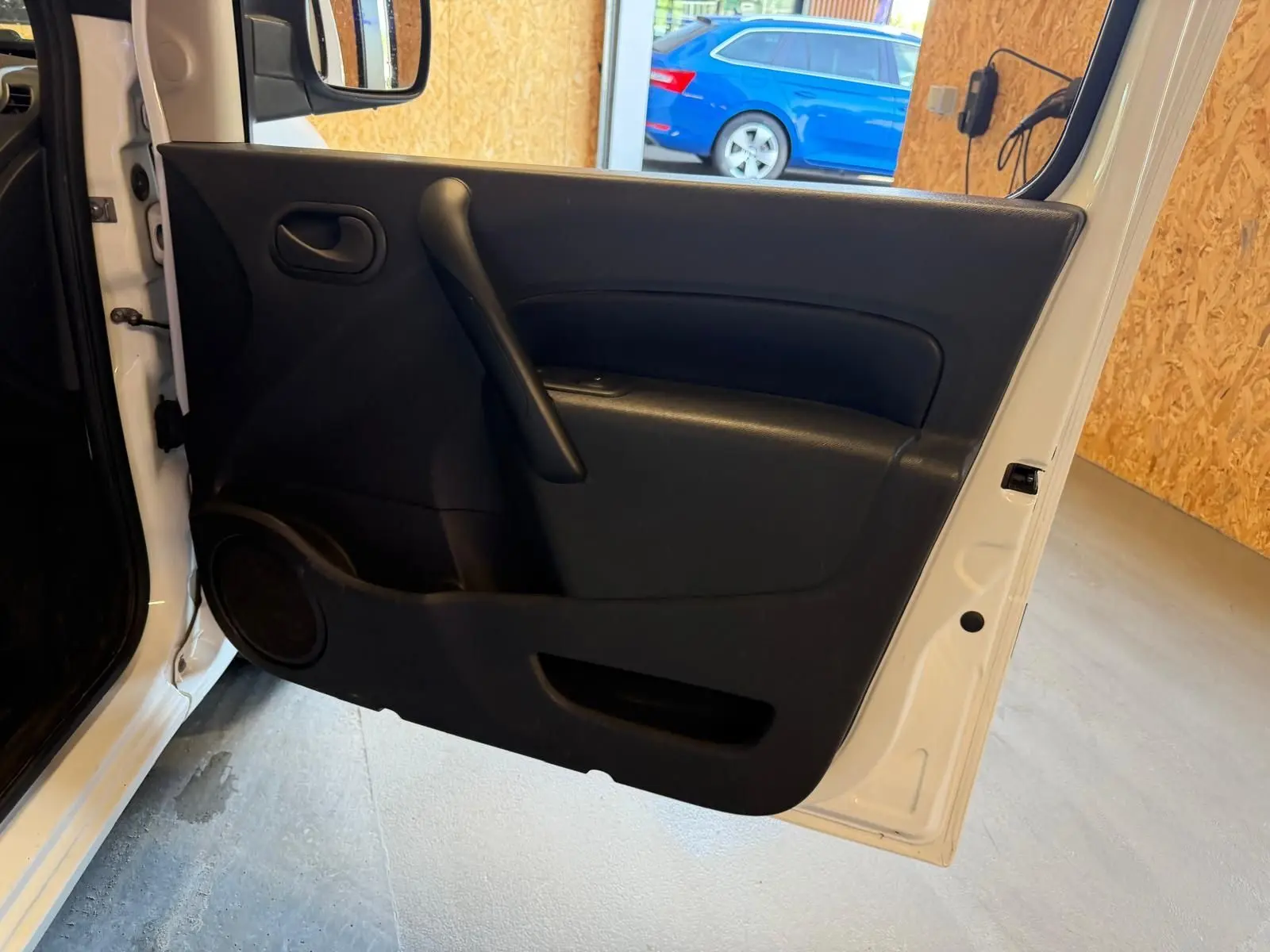 Vue intérieure de la porte avant gauche blanche d’un Renault Kangoo 1.5 DCI 85 Compact avec panneau noir et haut-parleur intégré.