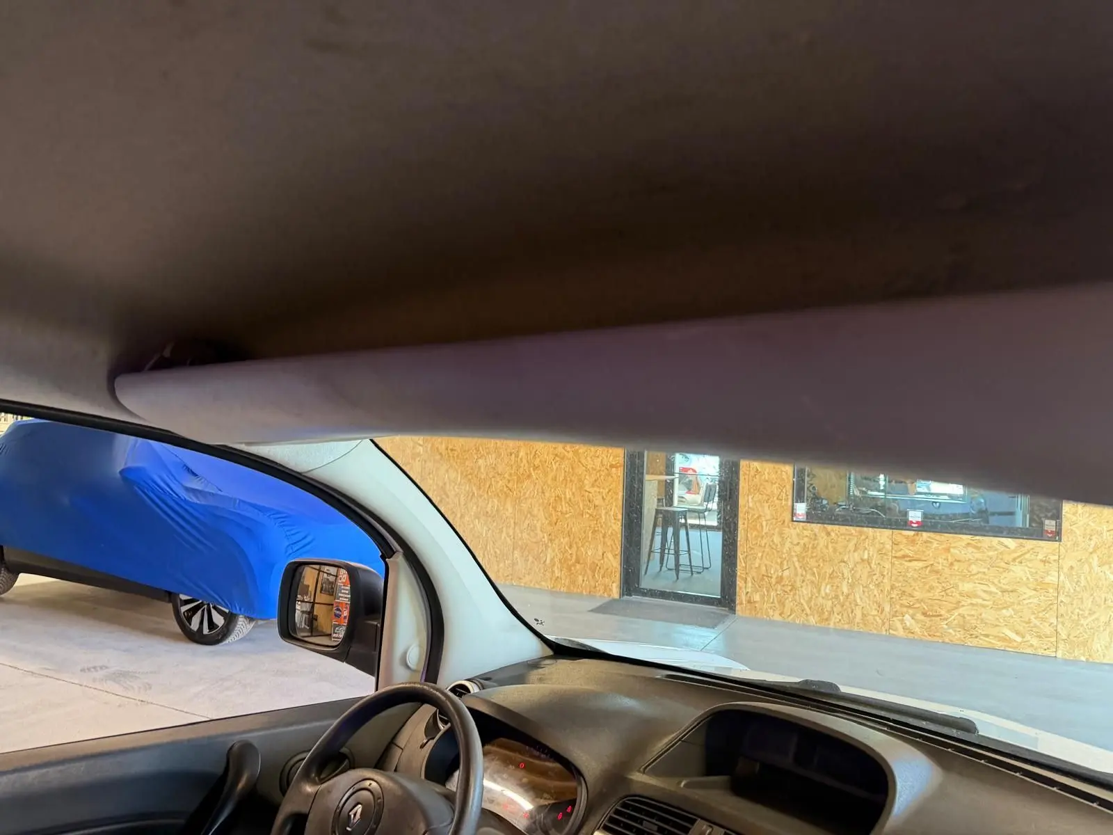Vue intérieure du Renault Kangoo blanc 2011, montrant le tableau de bord et le volant côté gauche avec intérieur noir.