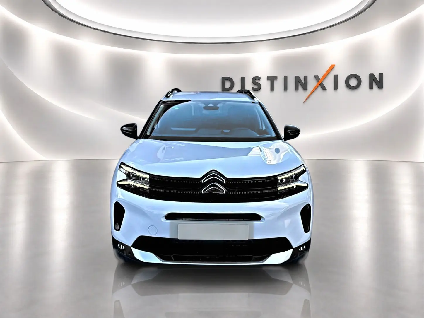 Vue frontale d'un Citroën C5 Aircross blanc 2025 avec calandre noire et barres de toit visibles en studio lumineux.