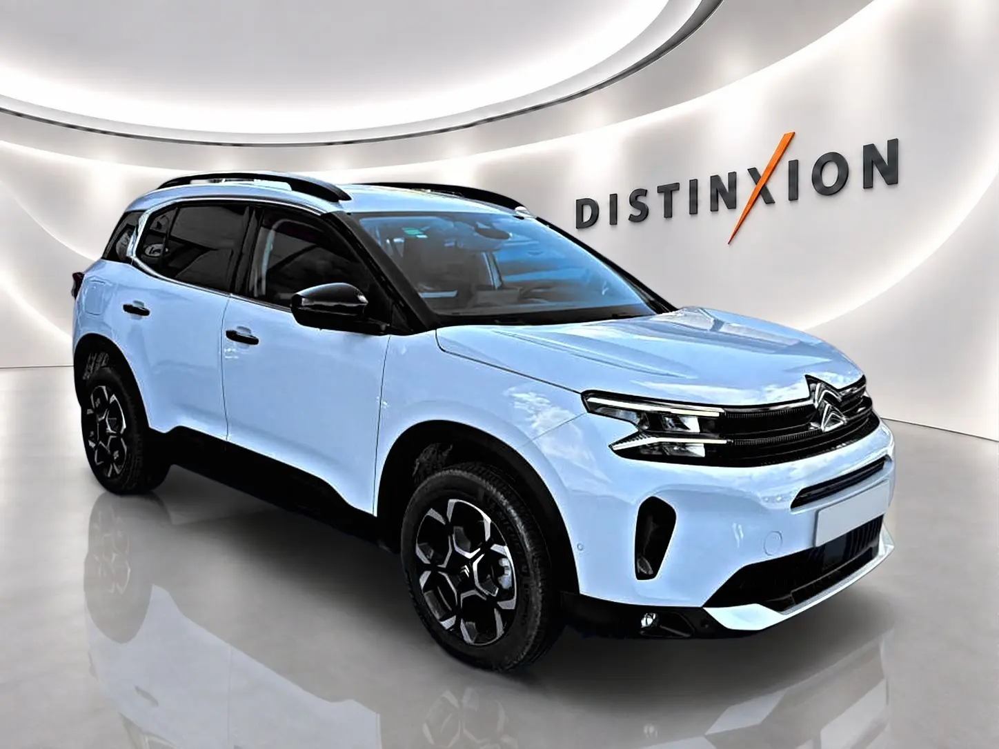 Citroën C5 Aircross blanc vue 3/4 avant droit avec toit noir et jantes alu distinctives en showroom.