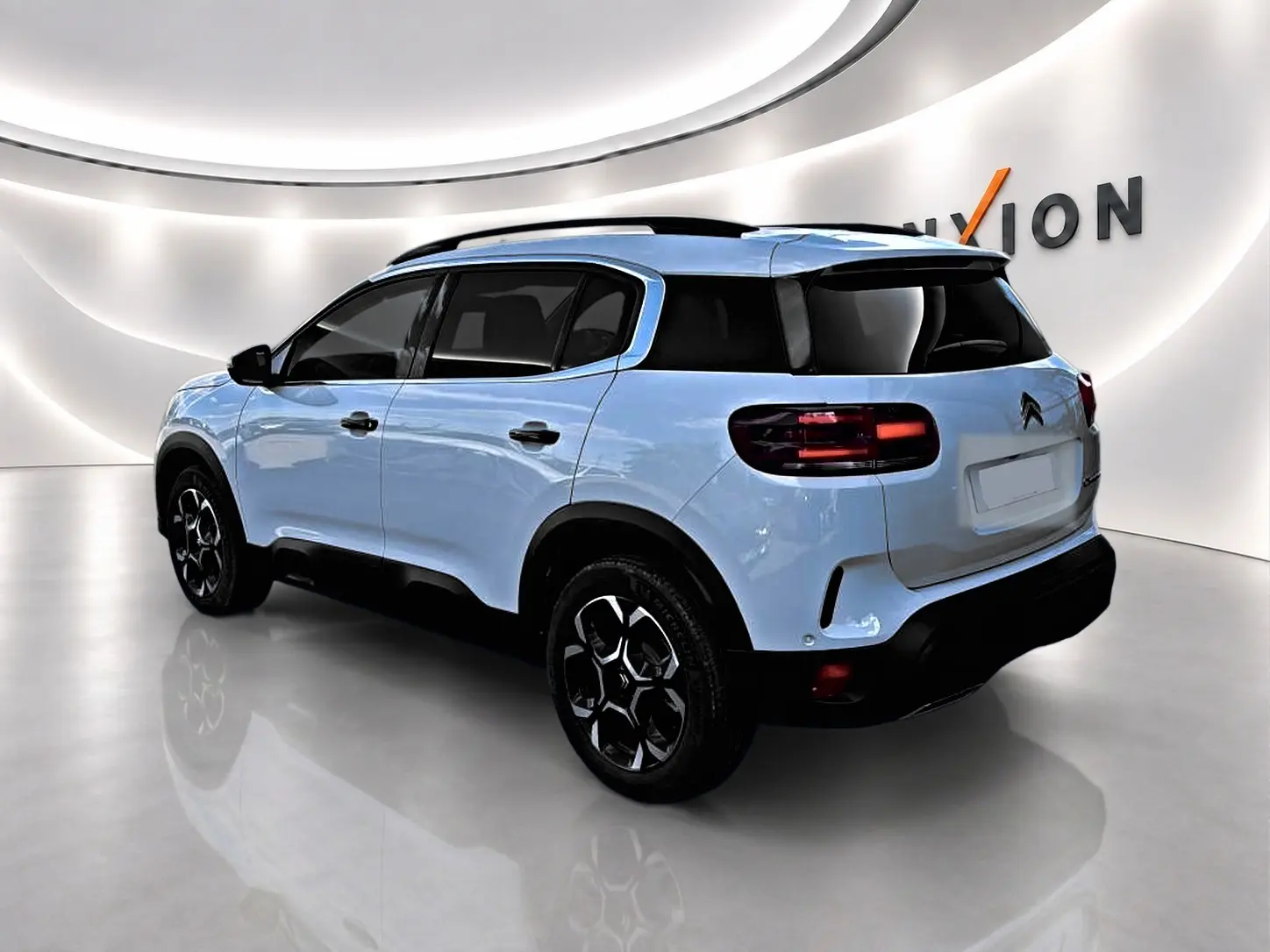 Vue 3/4 arrière droite du Citroën C5 Aircross blanc avec jantes noires et vitres arrière teintées dans un showroom.