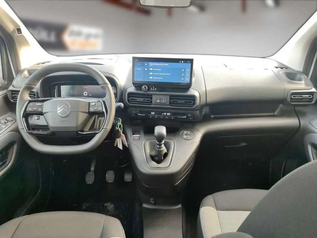 Vue intérieure avant du Citroën Berlingo gris artense, volant cuir multifonctions et écran tactile central visible.