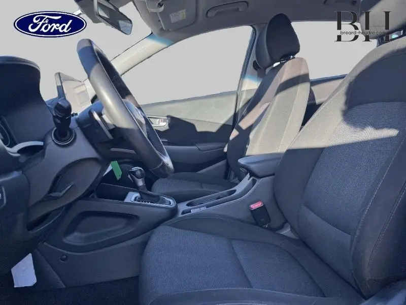 Vue intérieure côté conducteur du Hyundai Kona 1.6 GDi Hybrid Business 2022 avec sièges tissu noir et volant cuir multifonction.