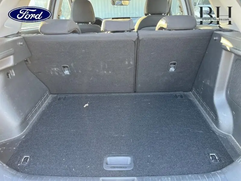 Vue du coffre arrière ouvert d'un Hyundai Kona 2022, intérieur noir avec banquette rabattable et espace de rangement.