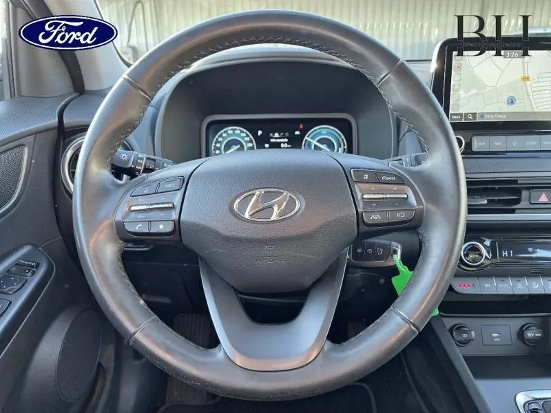 Vue intérieure centrée sur le volant cuir multifonction d'une Hyundai Kona 2022, avec tableau de bord et écran tactile visibles.