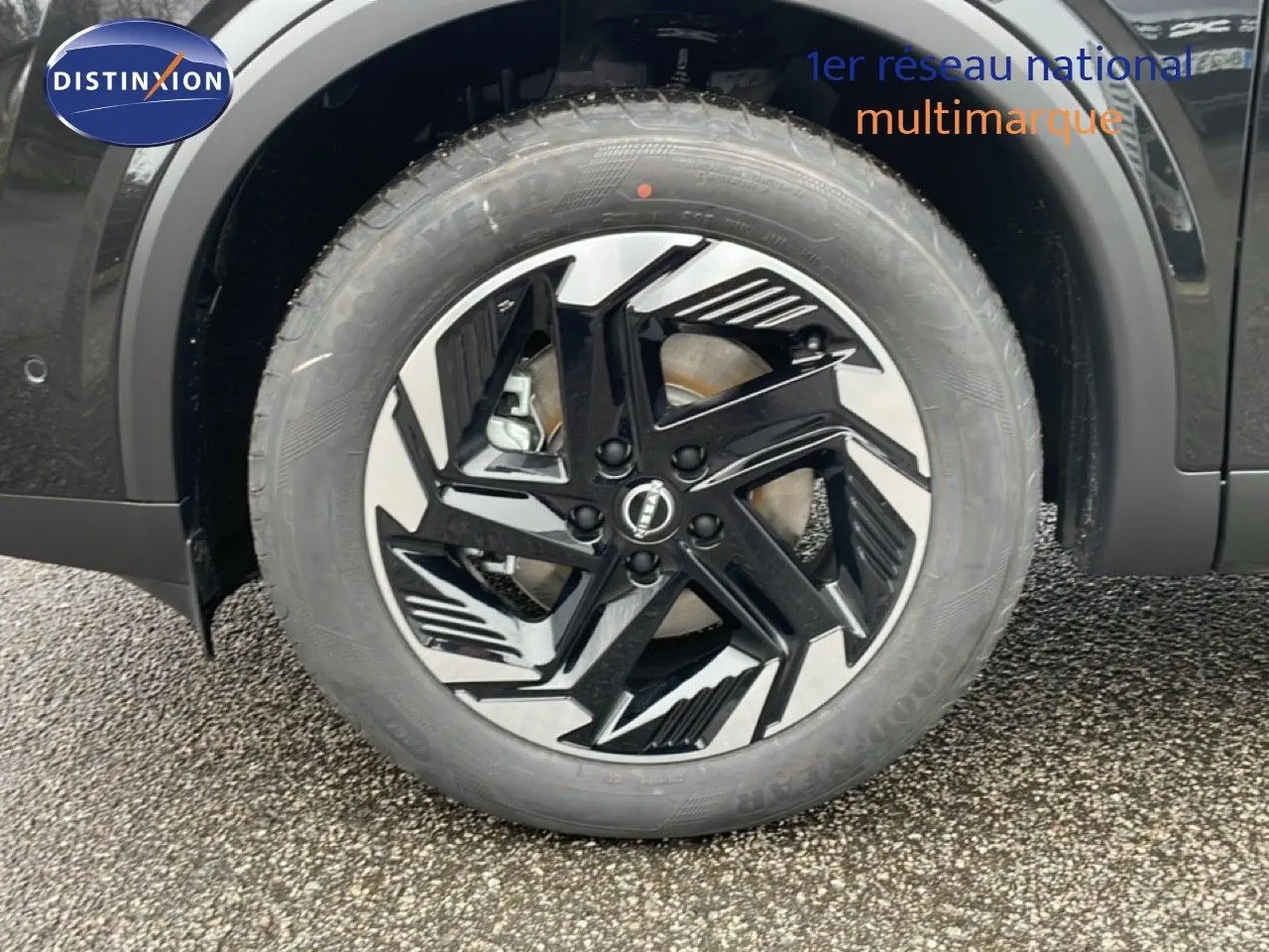 Gros plan sur la roue avant droite du Nissan Qashqai noir perle métal avec jante alliage noire et argentée au design géométrique.