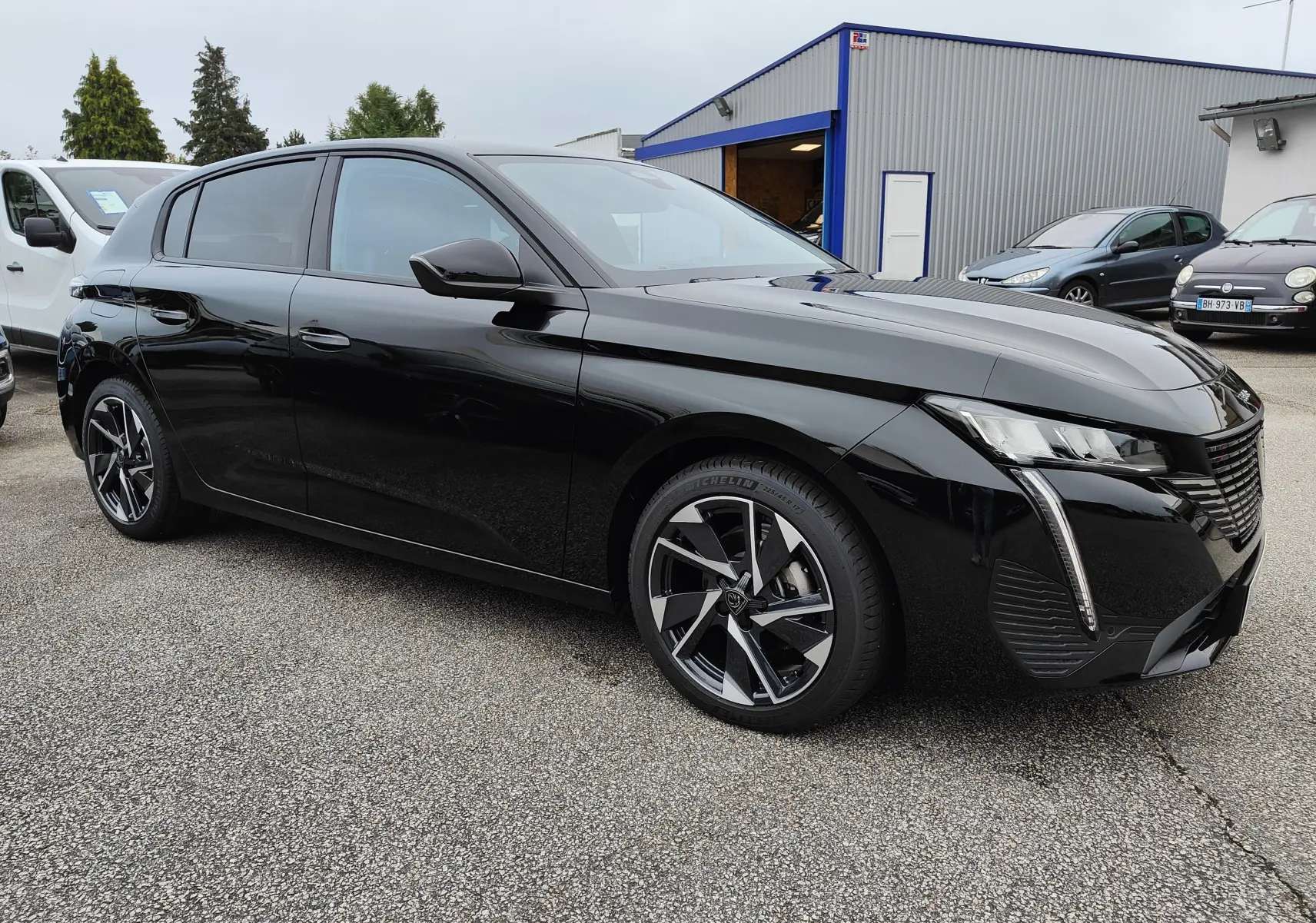 Peugeot 308 PureTech 130 Allure Pack noire vue en 3/4 avant droit, avec jantes bi-ton et phares LED distinctifs.