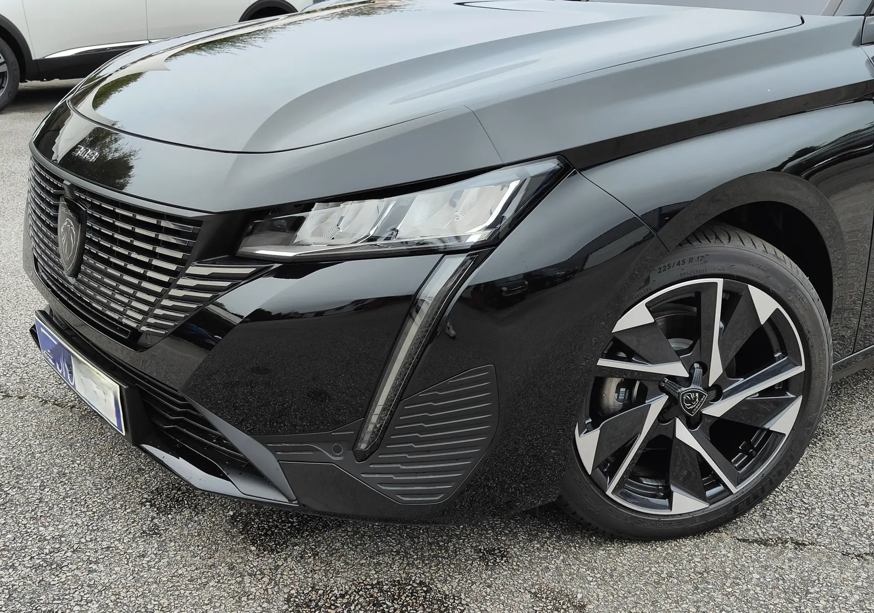 Vue 3/4 avant droit d'une Peugeot 308 PureTech 130 Allure Pack noire, mettant en valeur ses phares LED et jantes bi-ton.