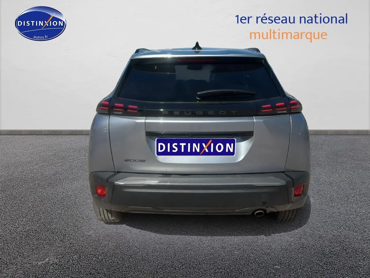 Vue arrière d'un Peugeot 2008 gris artense avec feux LED et lunette arrière surteintée, en extérieur sur sol goudronné.