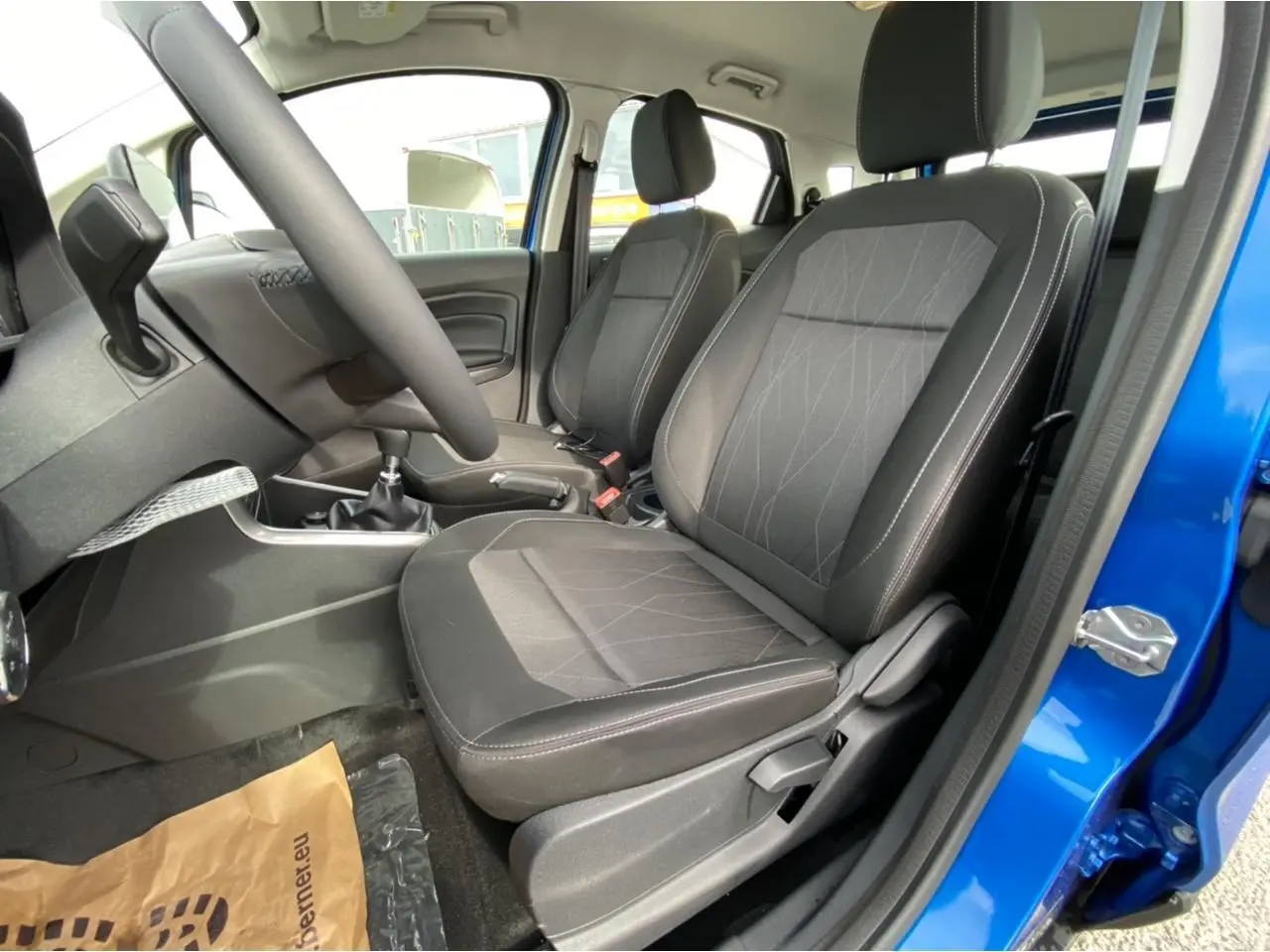 Vue intérieure côté conducteur du Ford EcoSport bleu Island 2022, sièges tissu noir avec coutures contrastées.