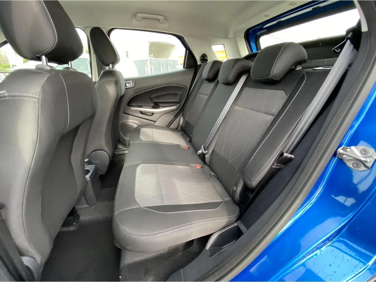 Vue intérieure de la banquette arrière noire du Ford EcoSport bleu Island, porte arrière droite ouverte.