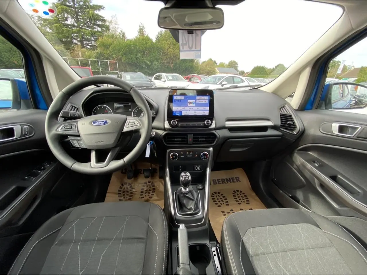 Vue intérieure avant du Ford EcoSport bleu Island 2022, montrant le volant, la boîte manuelle et l’écran tactile central.