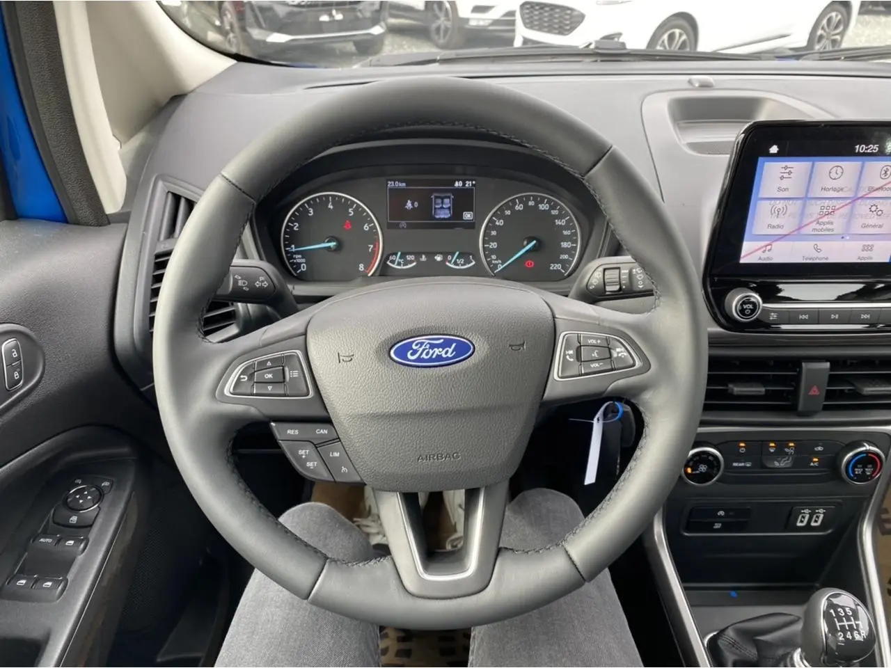 Vue intérieure centrée sur le volant Ford d'un EcoSport bleu Island, avec tableau de bord et écran tactile visibles.