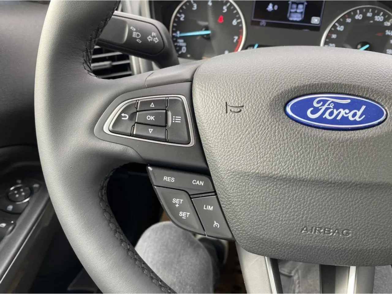 Gros plan sur le volant multifonction gris du Ford EcoSport 2022 avec commandes de régulateur et logo Ford visible.