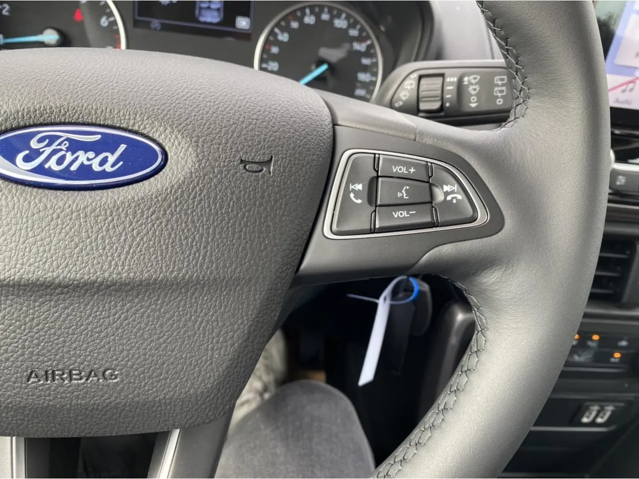 Gros plan sur le volant noir du Ford EcoSport 2022 avec commandes audio intégrées et logo Ford bleu au centre.
