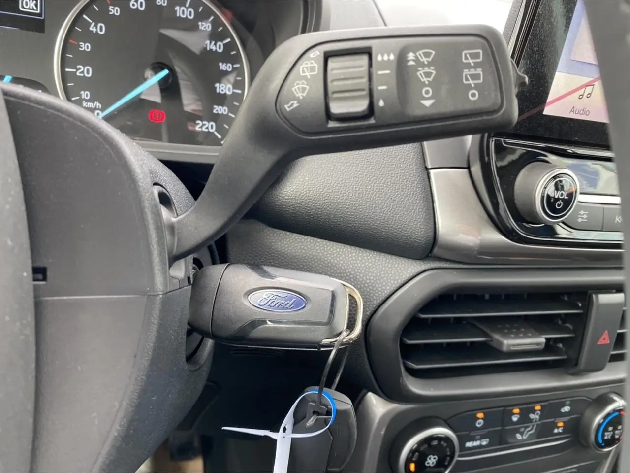 Vue rapprochée de l’intérieur du Ford EcoSport 2022, clé dans le contact et commandes de climatisation visibles.