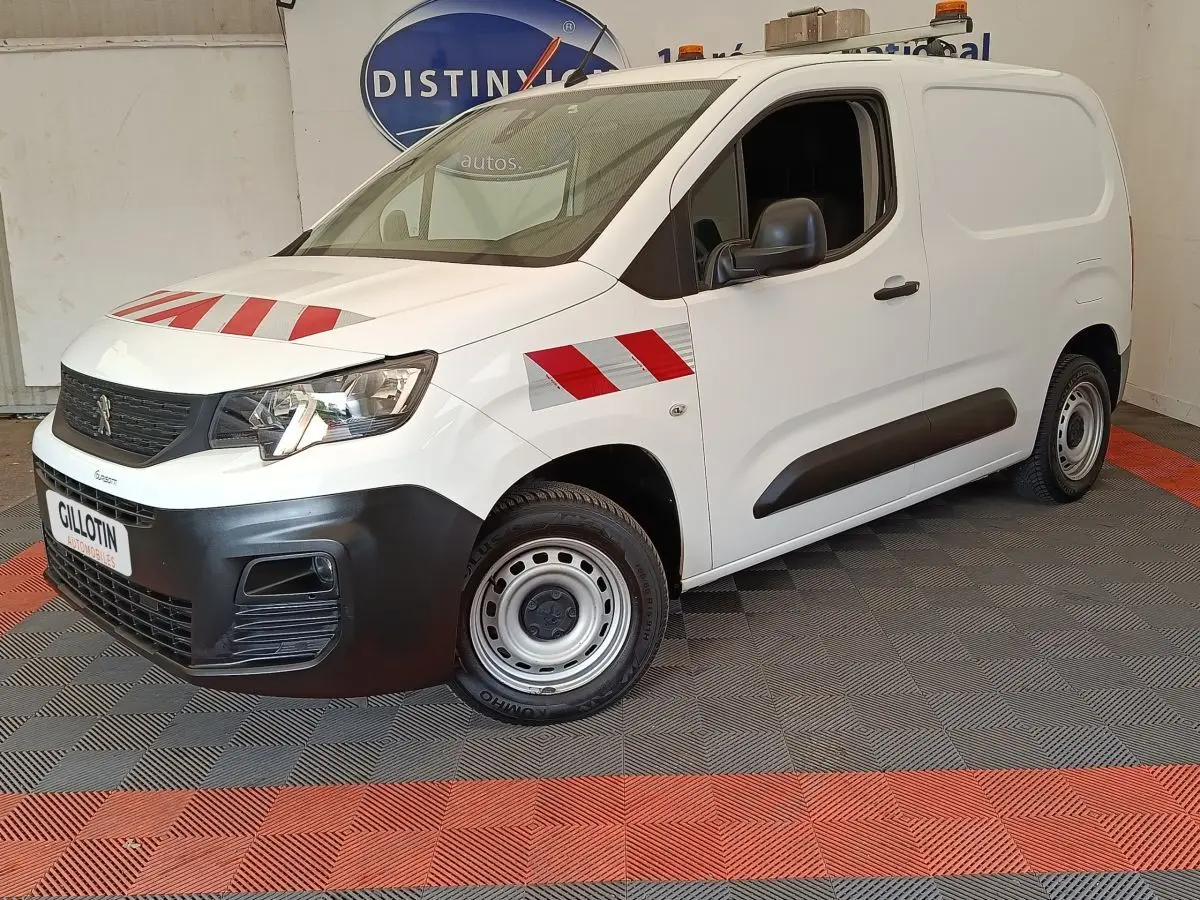 Vue 3/4 avant droit d’un Peugeot Partner blanc avec bandes rouges réfléchissantes sur capot et aile avant.