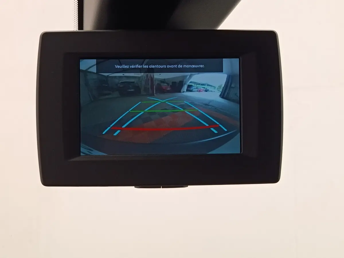 Écran intérieur affichant la caméra de recul du Peugeot Partner blanc, avec lignes de guidage colorées.