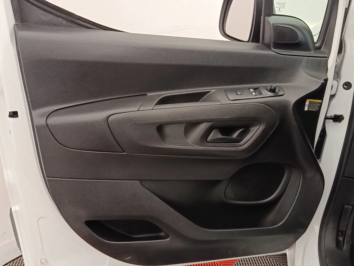 Vue rapprochée de la porte avant gauche noire du Peugeot Partner blanc, avec commandes de vitres et haut-parleur intégré.