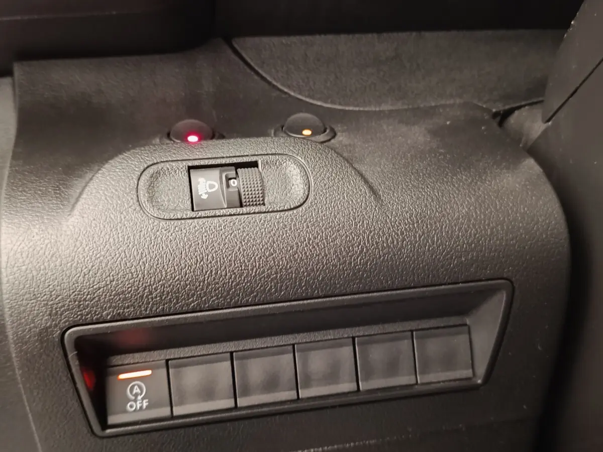 Gros plan sur le tableau de bord noir du Peugeot Partner 2022, montrant les commandes de réglage des phares et désactivation du start-stop.
