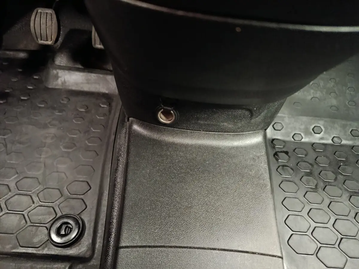 Vue rapprochée de la console centrale et des pédales d’un Peugeot Partner blanc, avec prise 12V visible.