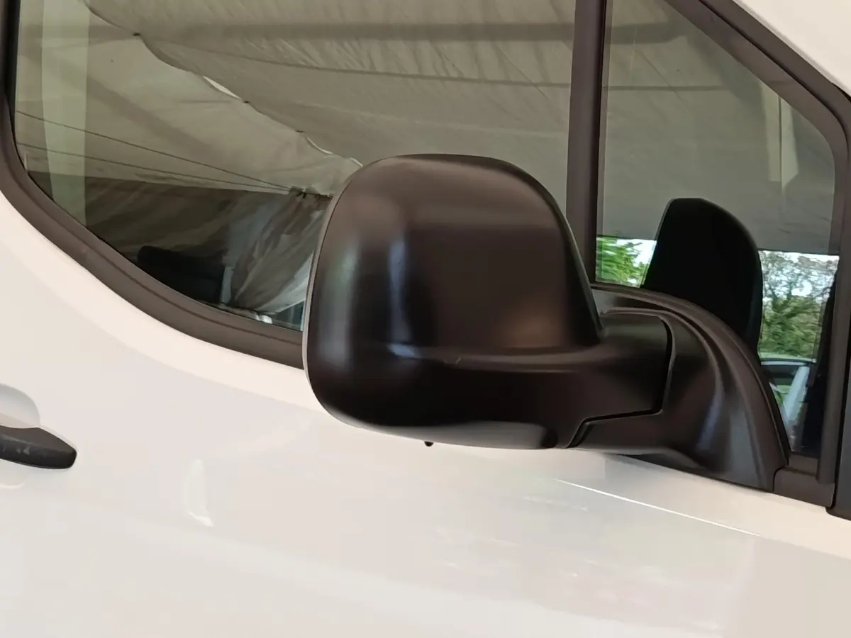 Gros plan sur le rétroviseur noir côté conducteur du Peugeot Partner blanc 2022, vue latérale rapprochée.