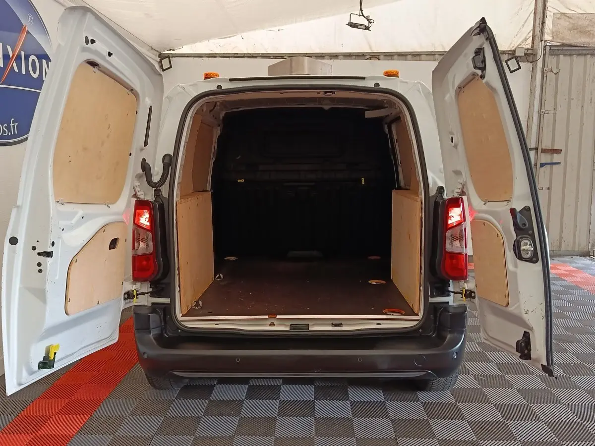 Vue arrière ouverte du Peugeot Partner blanc 2022 montrant l'espace de chargement avec cloison pleine et panneaux bois.