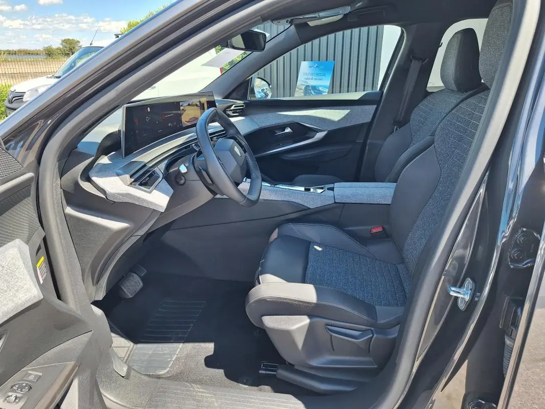 Intérieur avant droit du Peugeot 3008 Hybrid 136 Allure 2025 gris foncé, avec cockpit numérique et sellerie bi-matière.