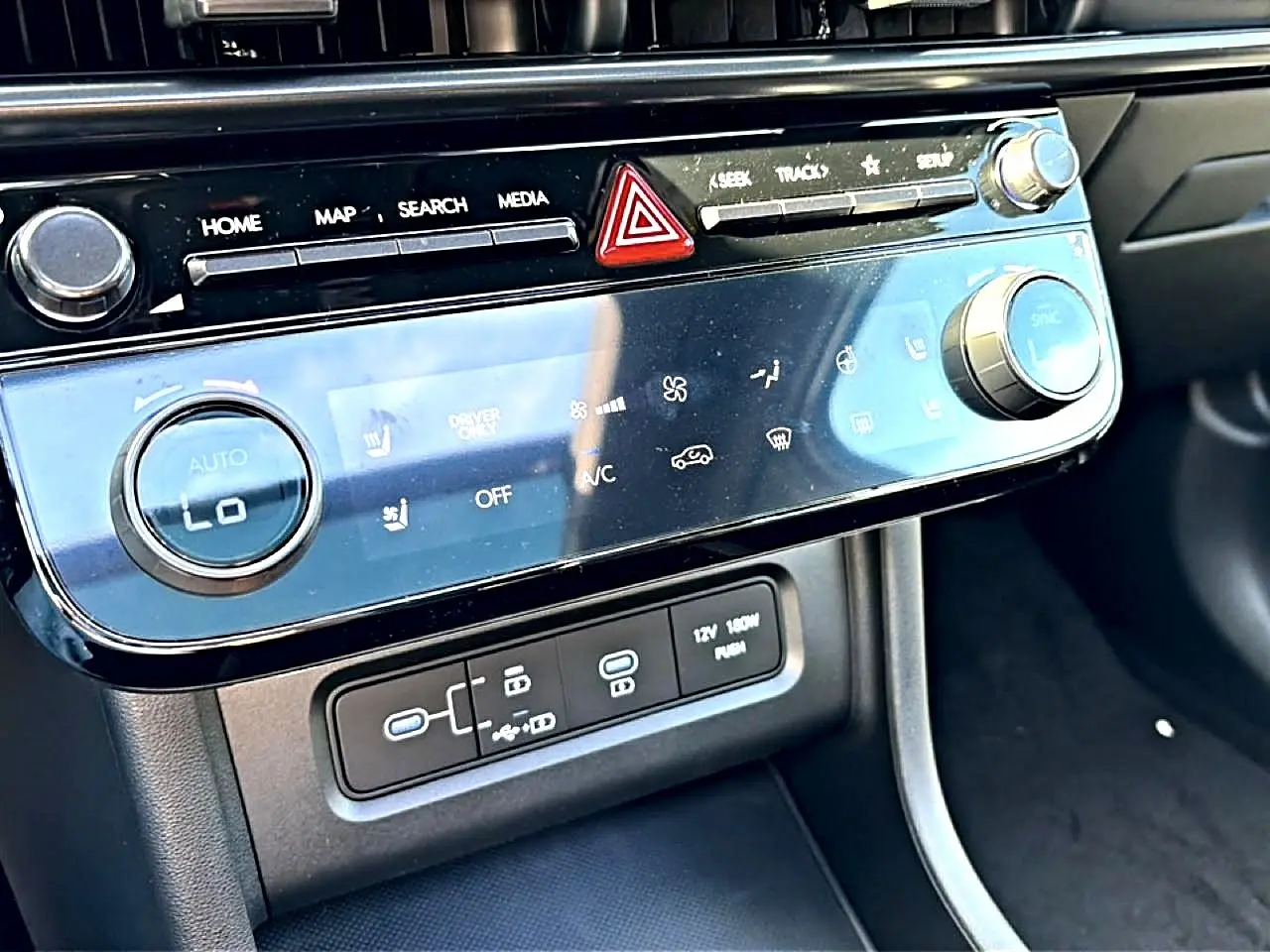 Vue rapprochée de la console centrale du Hyundai Tucson 2026, avec commandes climatisation et ports USB visibles.