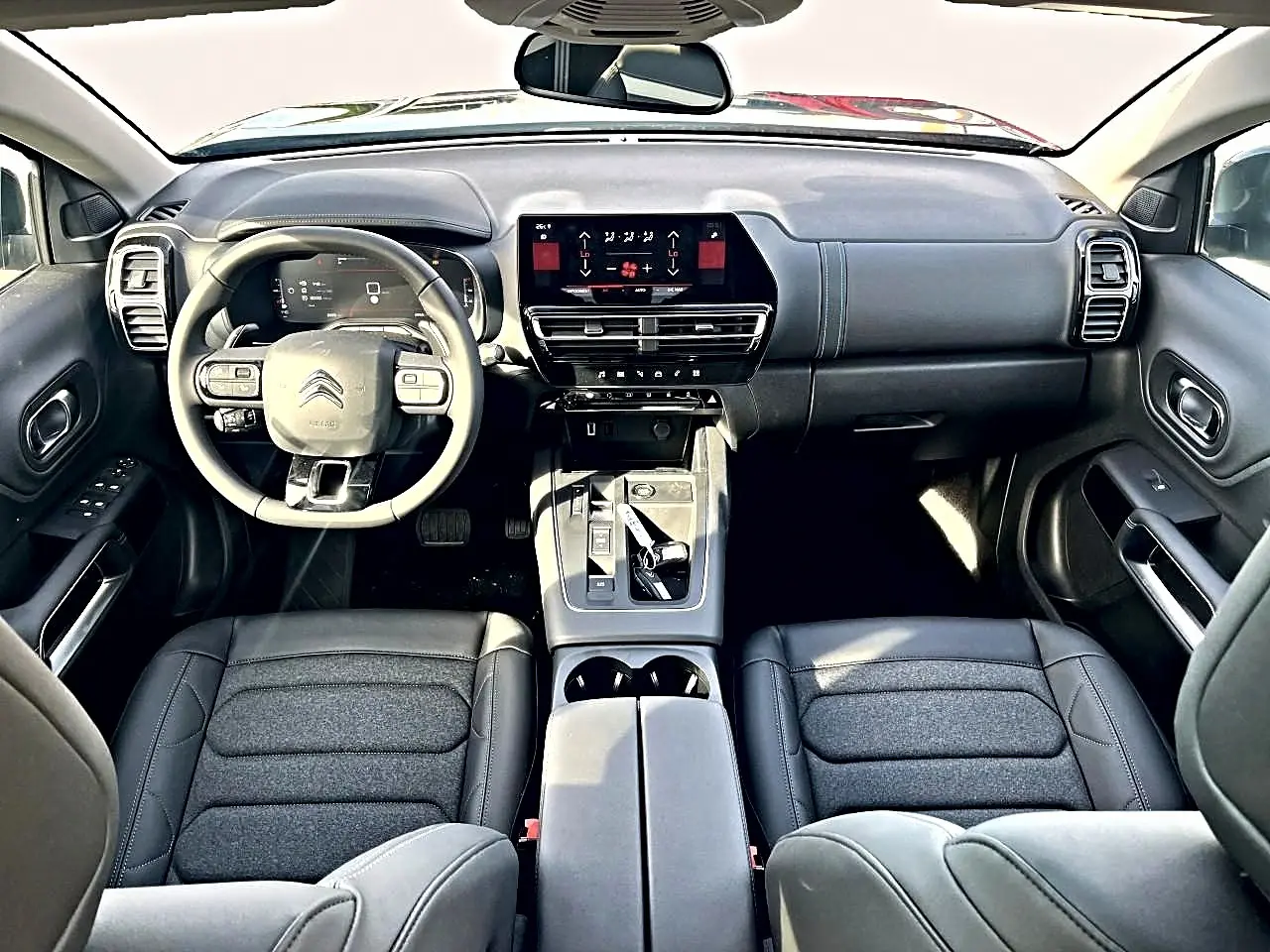 Vue intérieure avant du Citroën C5 Aircross 2025 noir, avec tableau de bord moderne et volant multifonction cuir.