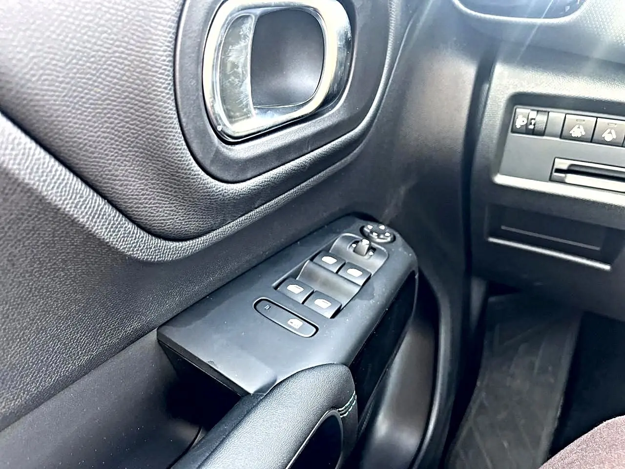 Gros plan sur la porte avant gauche noire du Citroën C5 Aircross 2025 avec commandes des vitres et poignée chromée.