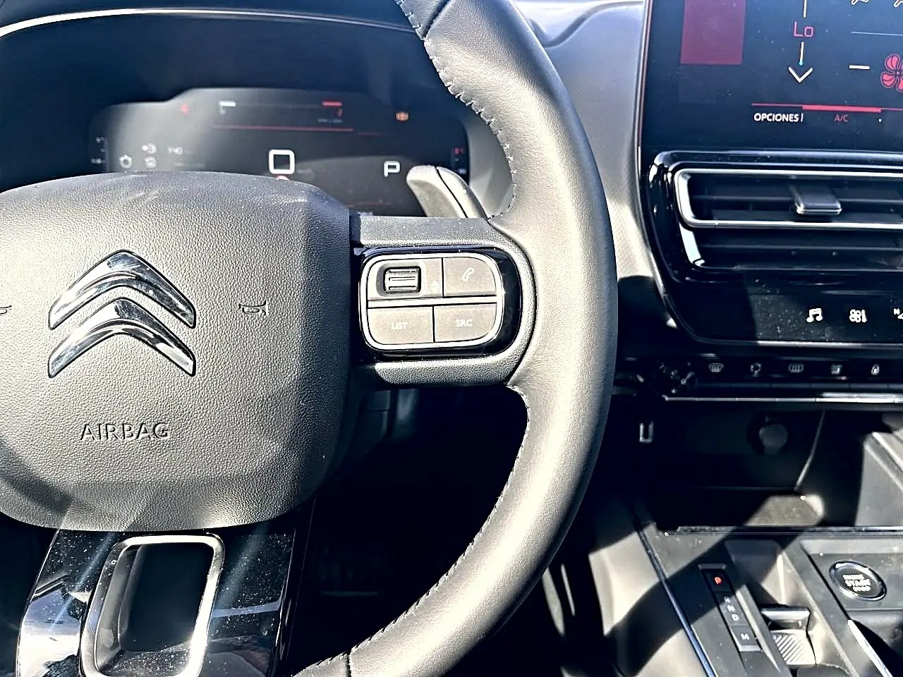 Vue rapprochée du volant cuir noir de la Citroën C5 Aircross 2025 avec commandes intégrées et tableau de bord numérique.