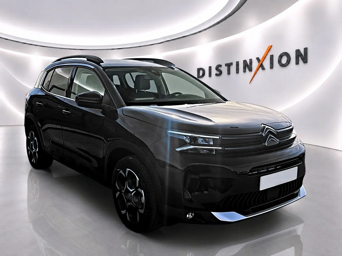 Citroën C5 Aircross noir vue 3/4 avant droit, avec barres de toit et jantes alliage distinctives dans un showroom.