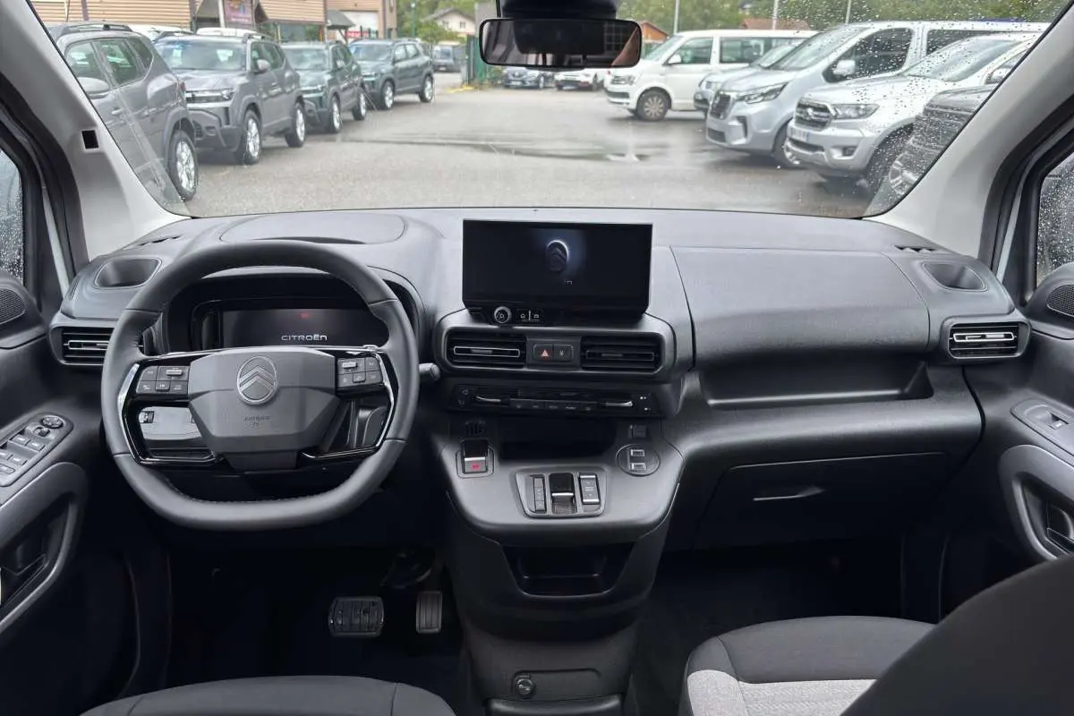 Vue intérieure avant du Citroën Berlingo Kaolin white 2026, tableau de bord moderne avec écran central et volant multifonctions.