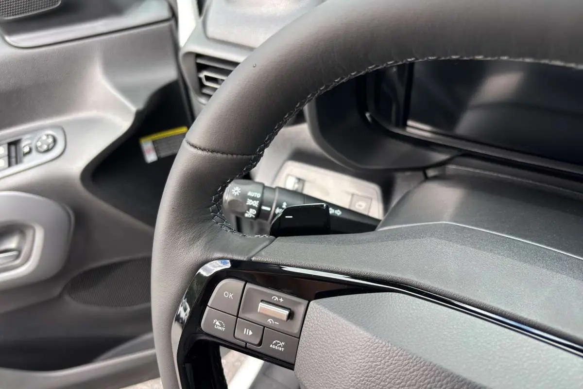 Gros plan sur le volant cuir noir multifonctions du Citroën Berlingo 2026 avec commandes intégrées et tableau de bord gris.