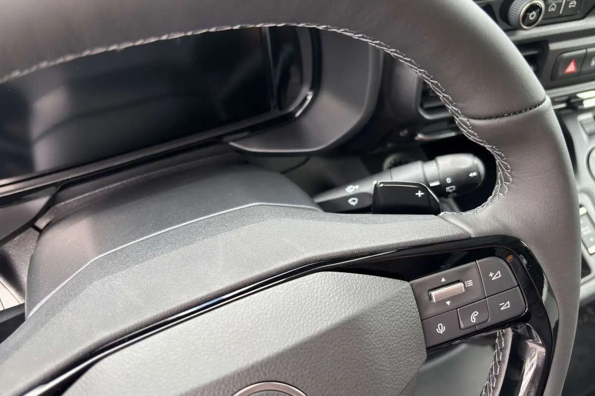 Gros plan sur le volant cuir multifonctions du Citroën Berlingo 2026, avec commandes intégrées et palettes au volant.
