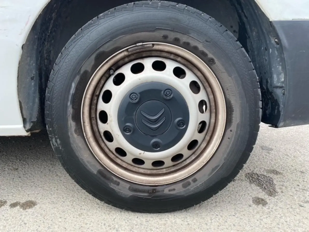 Gros plan sur la roue avant droite du Citroën Jumpy blanc, avec jante acier et logo Citroën central noir.