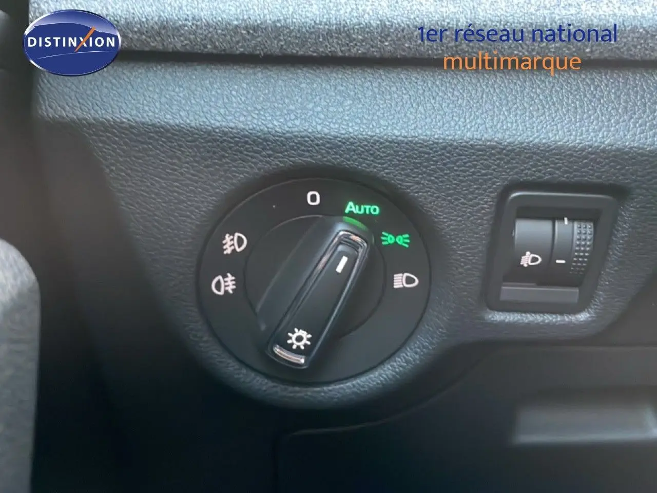 Gros plan sur le bouton de commande des phares du Skoda Kamiq 2025 en intérieur gris noir.