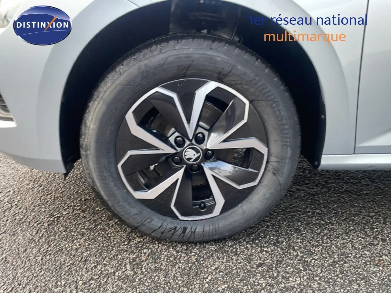 Gros plan sur la roue avant gauche d'un Skoda Kamiq gris argent métal avec jante alliage noire et argent.