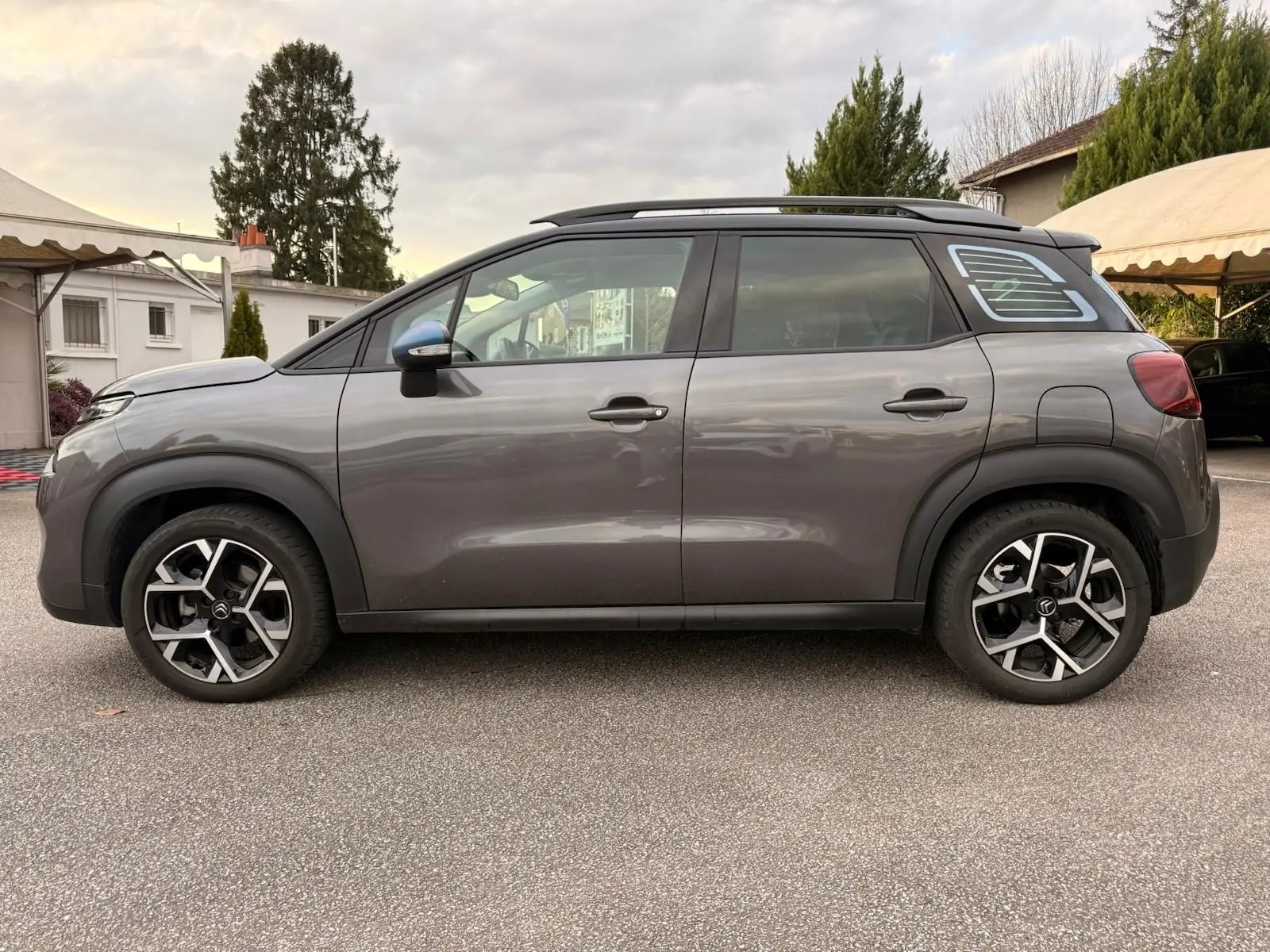 Vue de profil côté gauche d'un Citroën C3 Aircross gris platinium avec jantes alliage et toit noir contrasté.