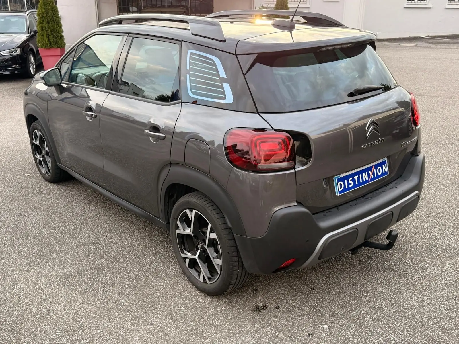 Vue 3/4 arrière droite d'une Citroën C3 Aircross gris platinium avec jantes noires et toit noir contrasté.