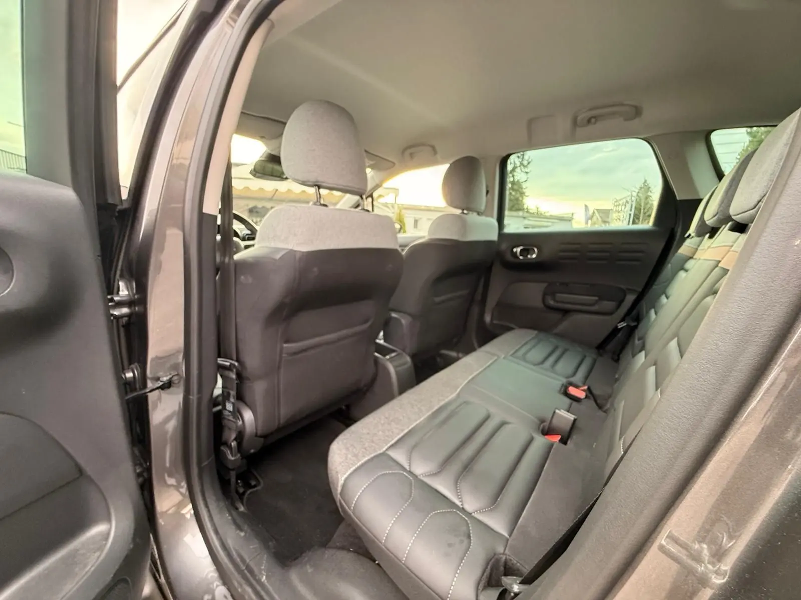 Vue intérieure arrière côté gauche de la Citroën C3 Aircross 2022 gris platinium, montrant les sièges arrière en tissu et cuir.