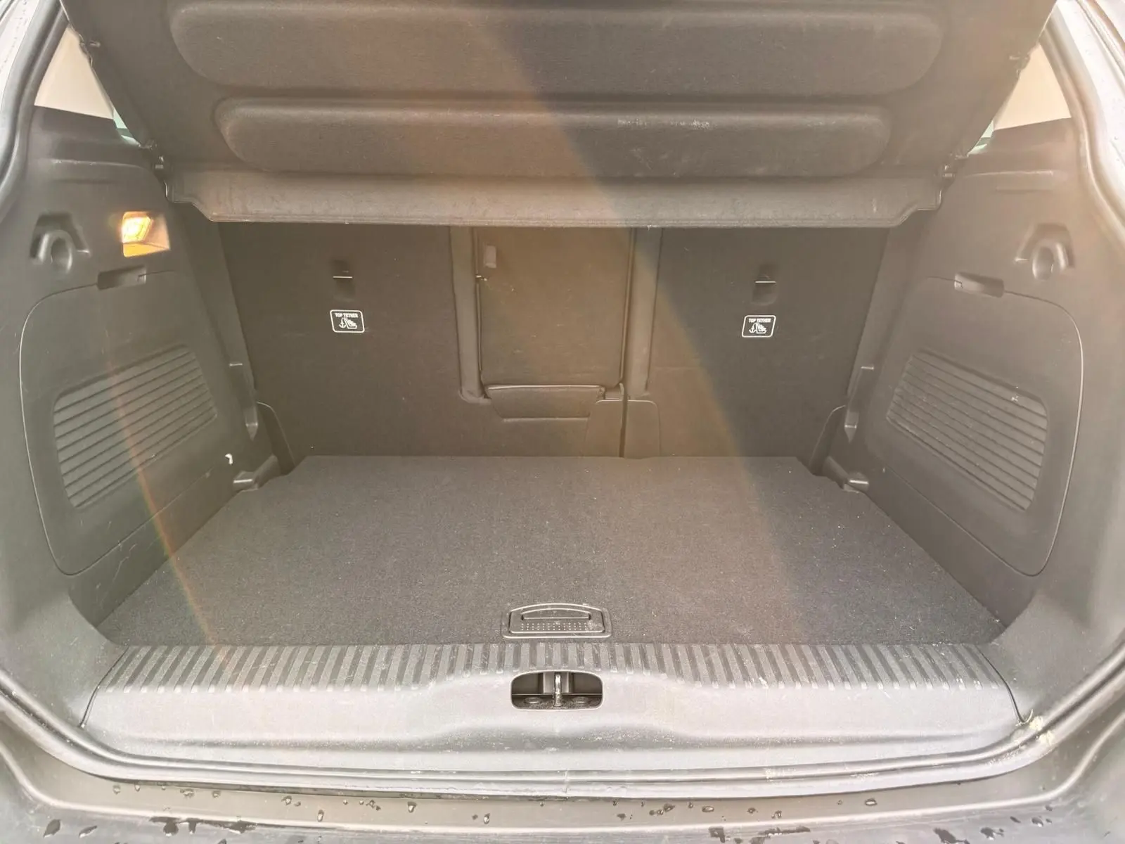 Vue intérieure du coffre spacieux et propre du Citroën C3 Aircross gris platinium, avec banquette arrière rabattue partiellement.