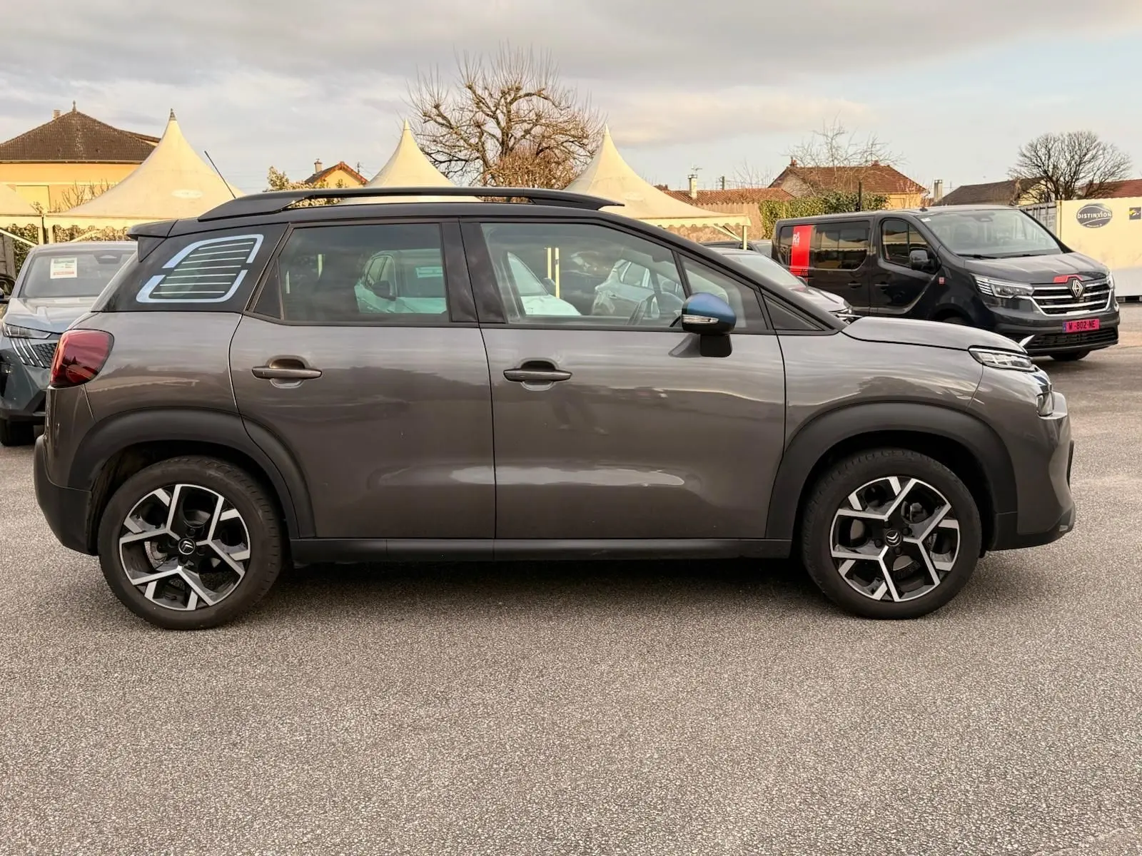Vue de profil côté gauche d'un Citroën C3 Aircross gris platinium 2022 avec toit noir et jantes alliage distinctives.
