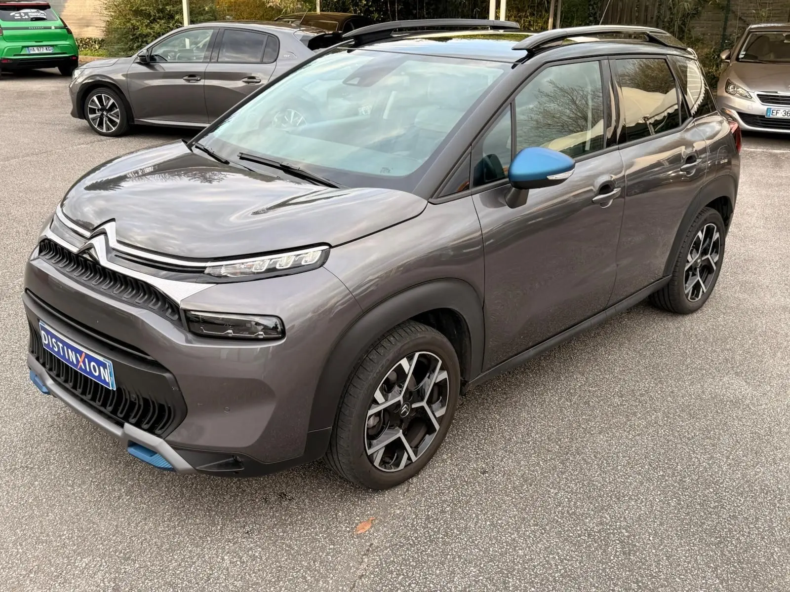 Citroën C3 Aircross gris platinium vue 3/4 avant droit, avec rétroviseur bleu et jantes noires stylées.
