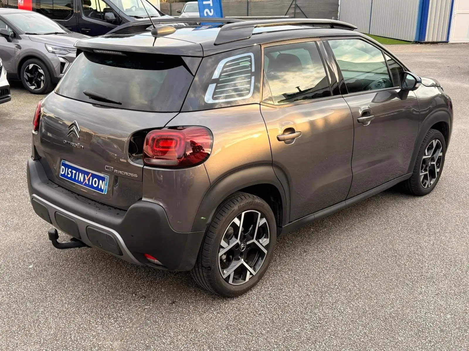 Vue 3/4 arrière droite d'un Citroën C3 Aircross gris platinium avec toit noir et jantes alliage bicolores.