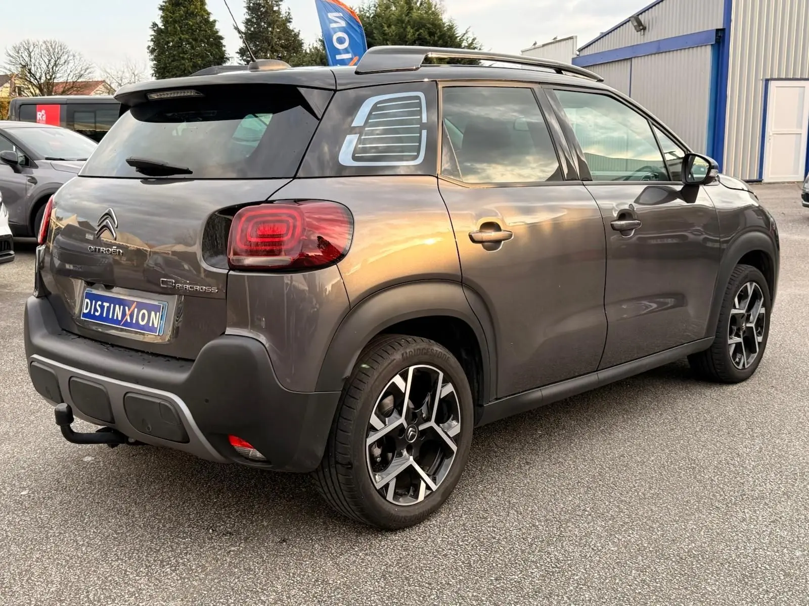 Vue 3/4 arrière droite d'un Citroën C3 Aircross gris platinium avec toit ouvrant et jantes alliage distinctives.