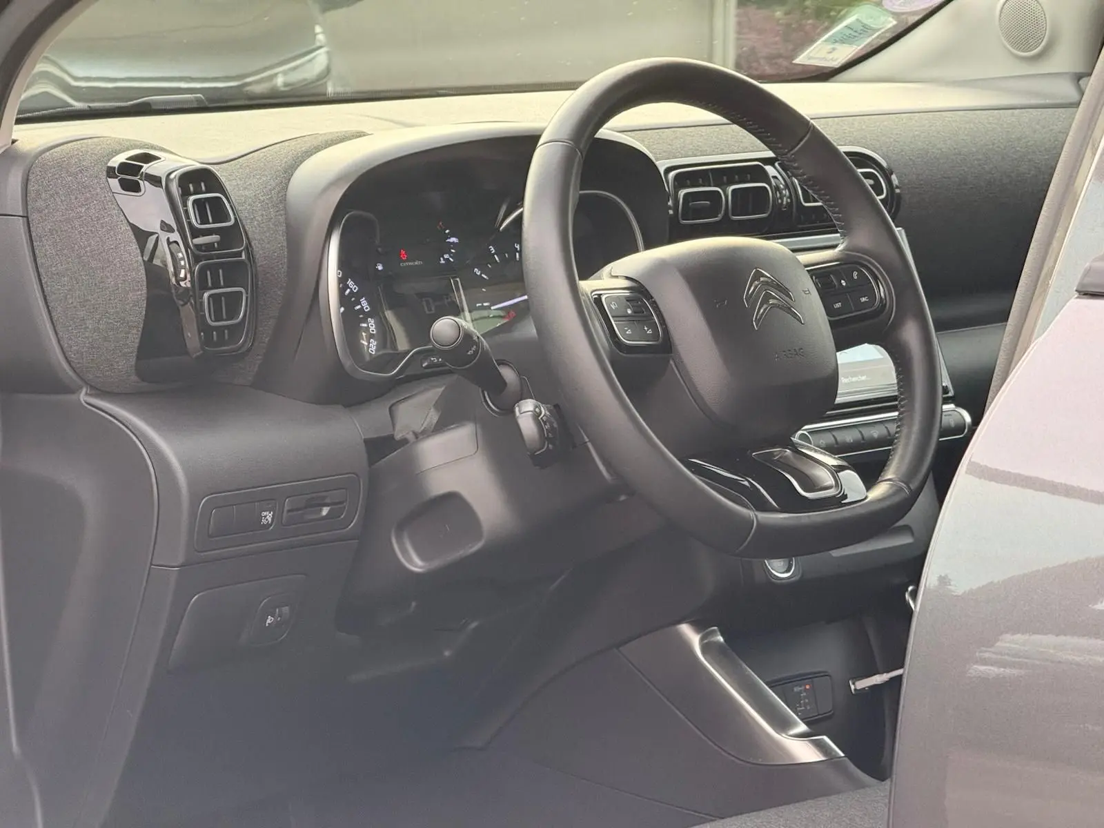 Vue intérieure côté conducteur du tableau de bord et volant noir du Citroën C3 Aircross gris platinium 2022.