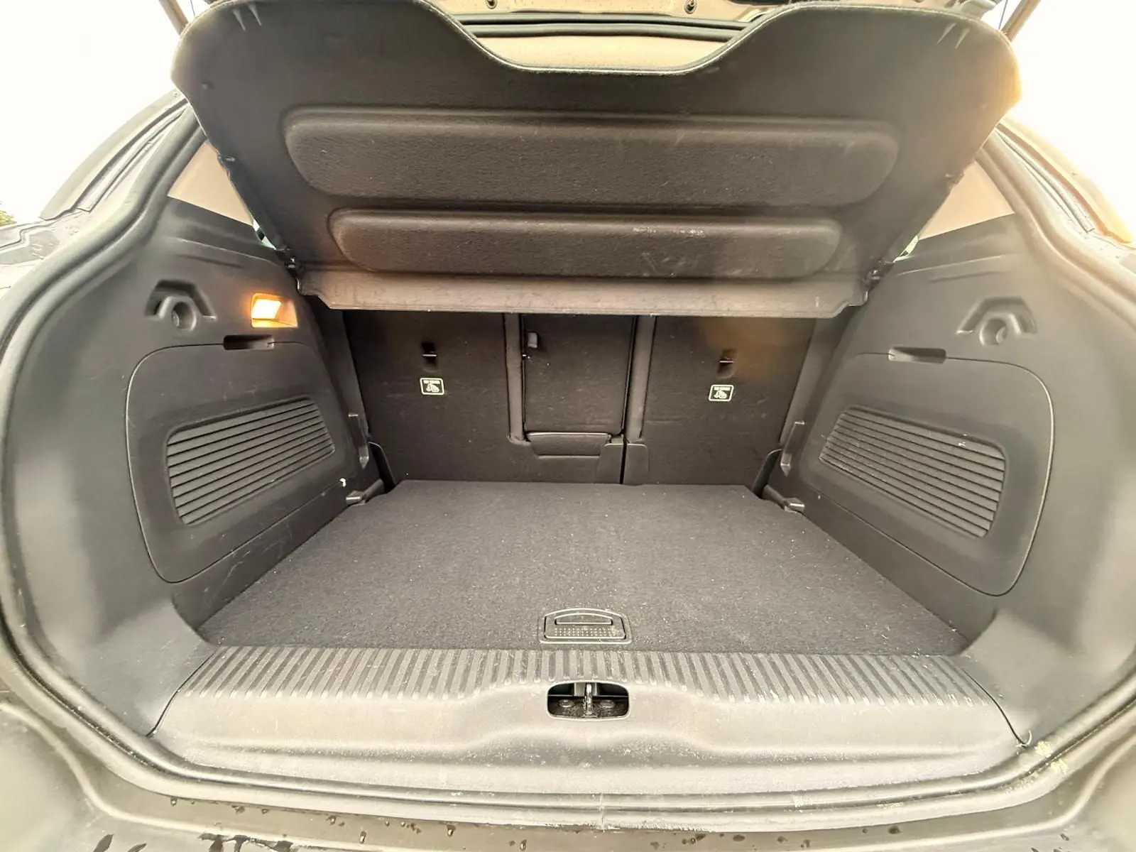 Coffre ouvert vu de l’arrière d’un Citroën C3 Aircross gris platinium, espace de chargement propre et spacieux.