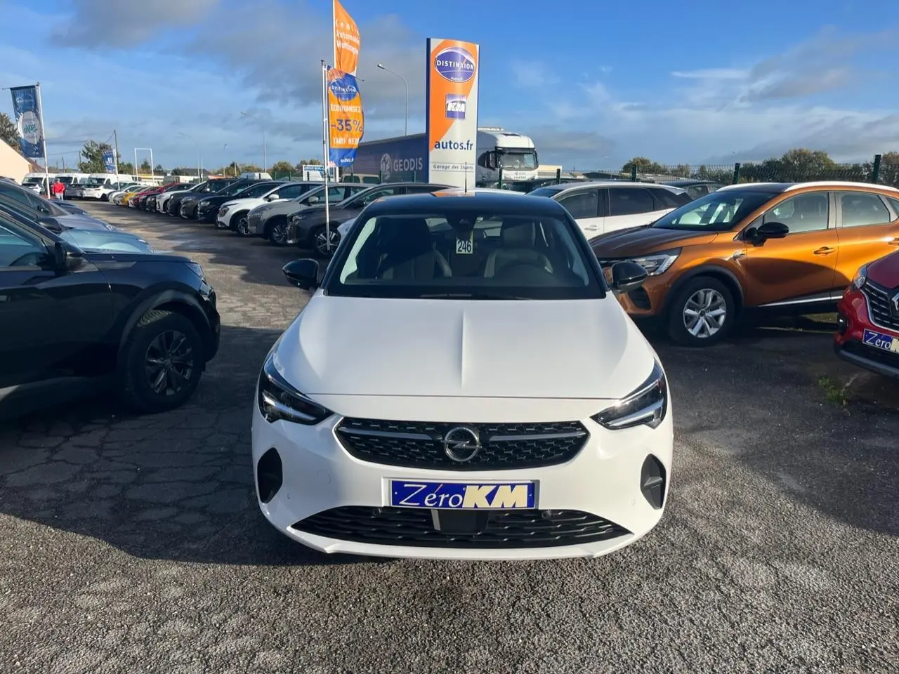 Vue avant d'une Opel Corsa blanche 2022 avec calandre noire et phares LED, stationnée en extérieur sur un parking.
